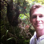 Smiling person standing in dense green foliage