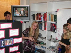 at the Alliance Française de Sacramento of a student explaining her exhibit to a guest