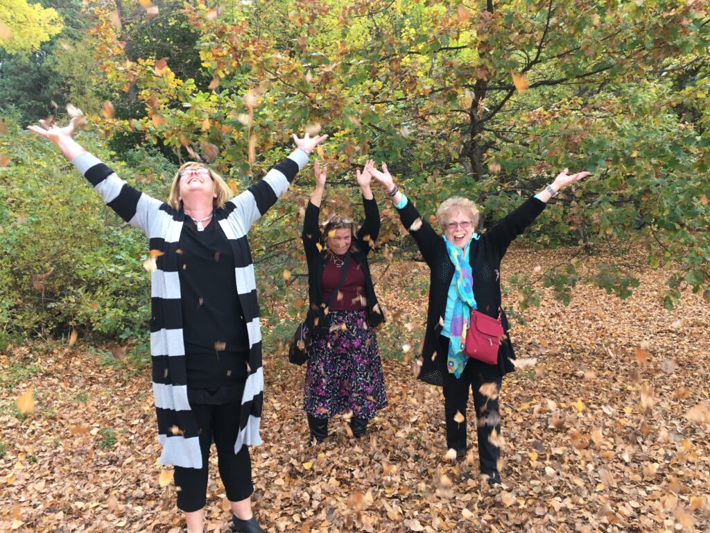 Anne Kenneally throwing leaves with Cynthia and Barbara