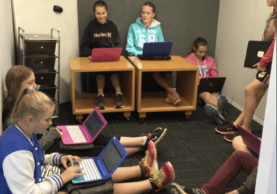 Students seated in a small room using laptops