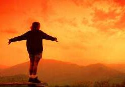 Person embracing sunset on mountain