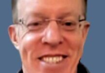 Man in glasses smiling against blue background