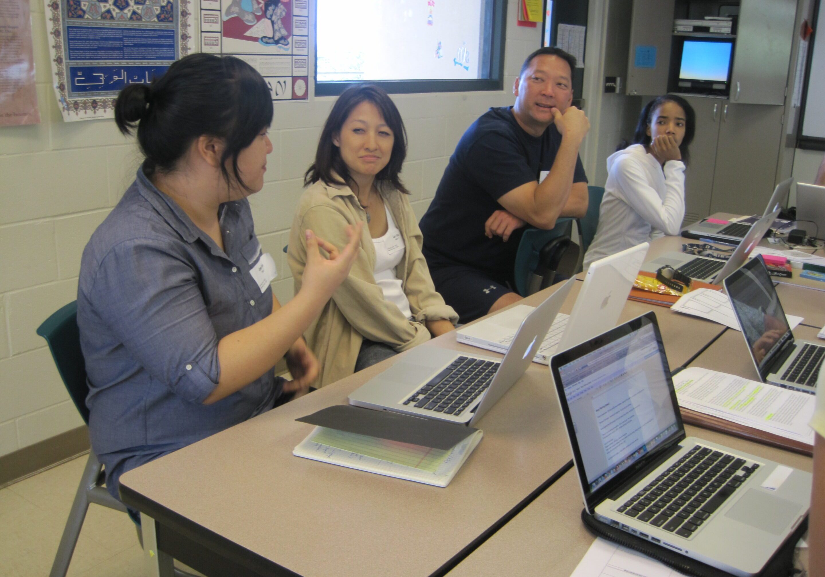 Four people engaged in a collaborative meeting with laptops open.