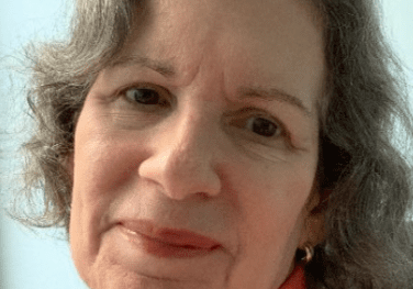 Woman smiling softly in orange turtleneck