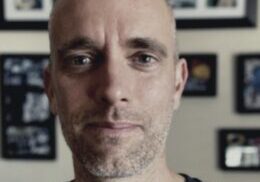 Individual standing indoors with picture frames