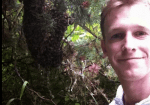 Smiling person standing in dense green foliage