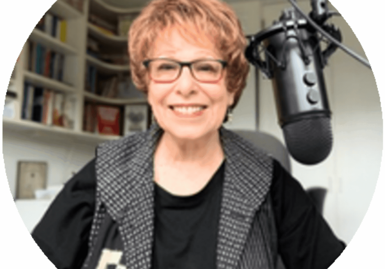 Person smiling in front of a microphone in a cozy room.