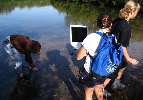 Group studying aquatic environment with laptop