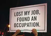 A sign reads, 'Lost my job, found an occupation.'
