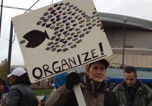 Person holding a sign that says 'ORGANIZE!' at a protest or rally.