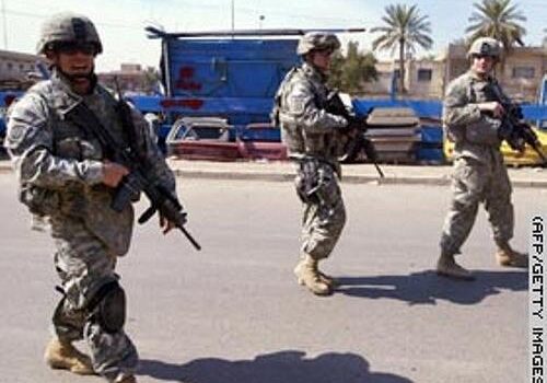 Three armed soldiers in military gear standing on a street during daytime.